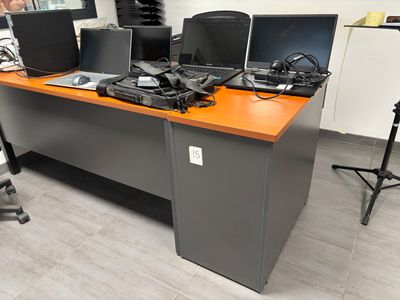 un bureau sur lequel sont posés de nombreux ordinateurs, dans une pièce