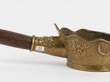 an old brass pot with a wooden handle on a white surface