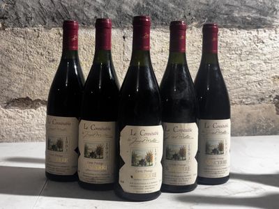 six bottles of wine are lined up on a table in front of a stone wall