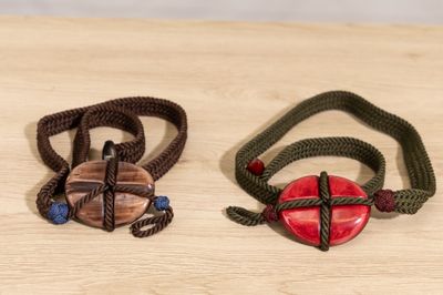 two bracelets with a red heart and a green cord on a wooden table