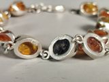 a close up of a bracelet with different colored stones on it