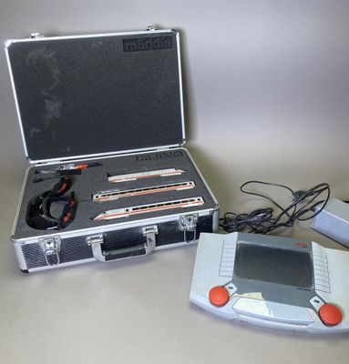 un boîtier argenté sur lequel figure un jeu, à côté d'une console de jeux