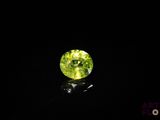 a green gemstone in the dark on a black surface
