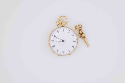 a gold pocket watch and a gold key on a white surface
