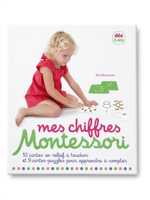 une petite fille assise par terre en train de jouer avec un livre