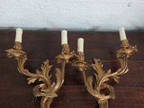 une paire d'appliques murales anciennes en laiton, avec des bougies posées sur une table en bois