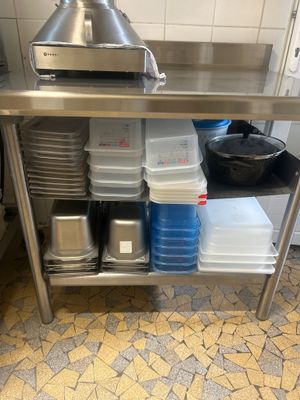 a stainless steel work table with pots and pans on it