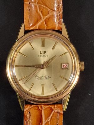 a gold watch with a brown leather strap on a black surface
