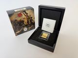 une pièce d'or dans une boîte noire posée à côté d'une boîte de cartes