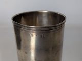 an old silver cup sitting on top of a glass table