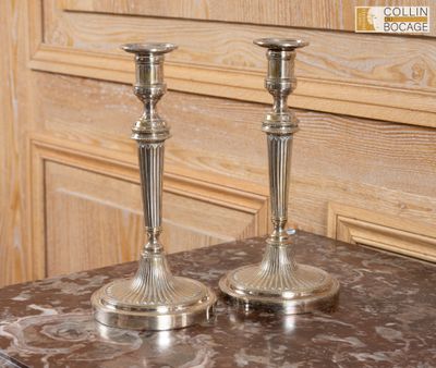 deux bougeoirs en argent posés sur une table en marbre