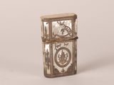 an old silver lighter with a clock on it sitting on a white surface