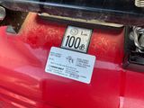 a close up of a red car with a number plate on it ' s bumper