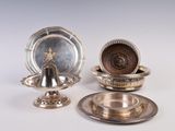 deux plats en argent et une assiette en argent posés sur un plateau blanc