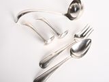 une cuillère, une fourchette et un repose-cuillère posés sur une surface blanche