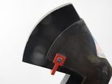 a black sculpture with a red handle on top of it