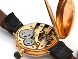 a close up of a pocket watch with a leather strap