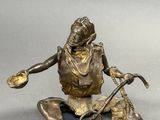bronze statue of a woman sitting on the ground with a dog
