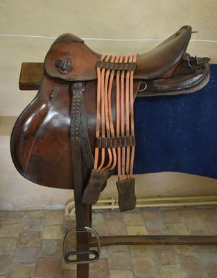 a brown saddle with a blue blanket on a stand