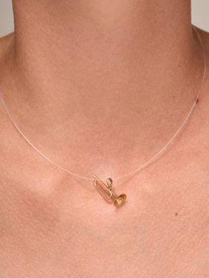 a close up of a woman wearing a gold necklace with two small gold hearts on it