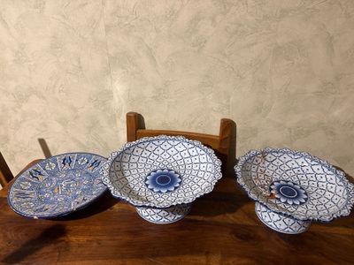 three blue and white plates sitting on top of a wooden table
