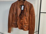 une veste en cuir marron suspendue à un porte-manteau dans une pièce