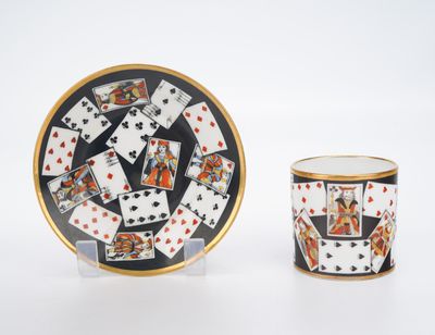 an image of a cup and saucer with playing cards on it