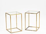 a pair of brass side tables with glass tops