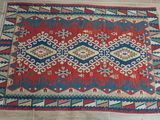 a red, blue and green rug on a tiled floor