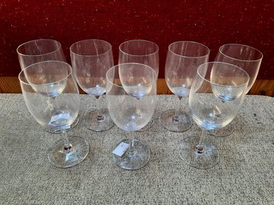 six empty wine glasses sitting on a table with a red wall in the background