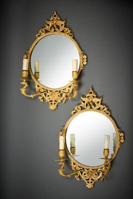 deux miroirs dorés, flanqués de bougies de chaque côté, accrochés au mur