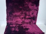 a close up of a purple pillow on a white surface