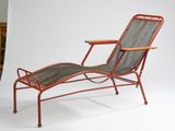 a red metal lounge chair with a tray on top of it