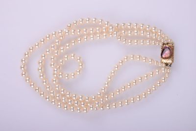a close up of a necklace with pearls on a white background