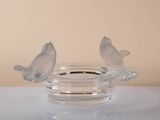 two birds sitting on a glass bowl on a table