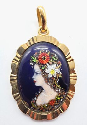 Un pendentif plaqué or représente une femme avec des fleurs dans les cheveux.