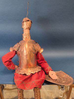 une statue représentant un homme en armure, assis sur un banc