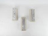 three pieces of metal sitting on a white surface