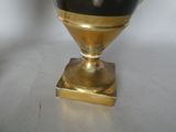 a black and gold vase sitting on top of a white table