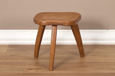 une image représentant un tabouret en bois posé sur un parquet en bois massif