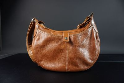 un gros plan d'un sac à main en cuir marron posé sur une surface noire