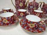 five cups and two saucers and a teapot on the table