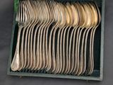a lot of silver spoons and forks in a box