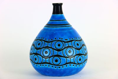 un vase bleu orné d'un motif, posé sur une table