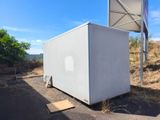 a small white box sitting on the side of the road