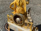 une statue représentant une femme assise sur un banc avec un chat