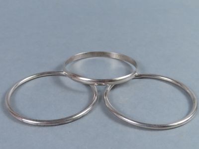 trois bagues en argent superposées sur un fond bleu