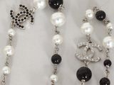 a black and white beaded necklace with a chanel charm
