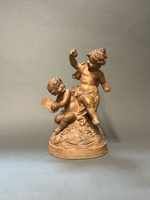 statue représentant un garçon et une fille jouant avec un éventail posé sur une table