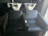 two black chairs in a room with two sinks and a mirror